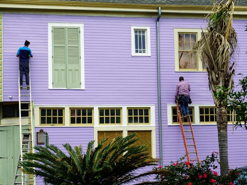 Two painters working from ladders on a facade